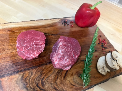 Two Tenderloin steaks on a board of garnishments