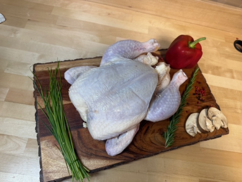 A whole chicken on a board of garnishments
