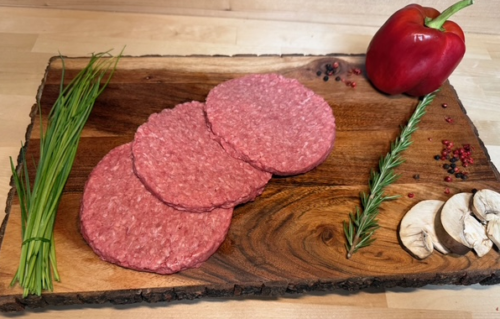 Three third pound patties on a board of garnishments