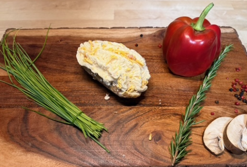 A twice baked potato on a board of garnishments