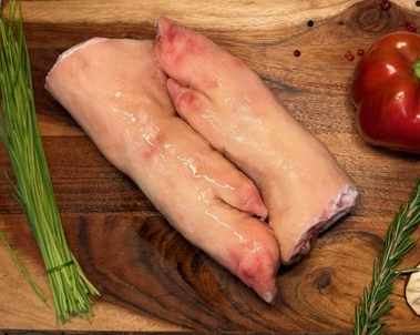 Two pigs feet on a board of garnishments