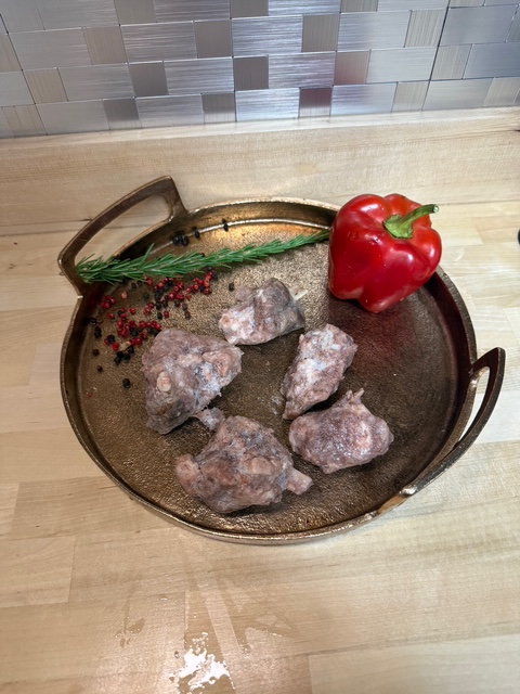 Five pieces of cooked hog wings on a plate of garnisments.