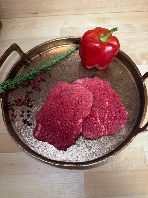 Two cube steak patties on a plate of garnishment