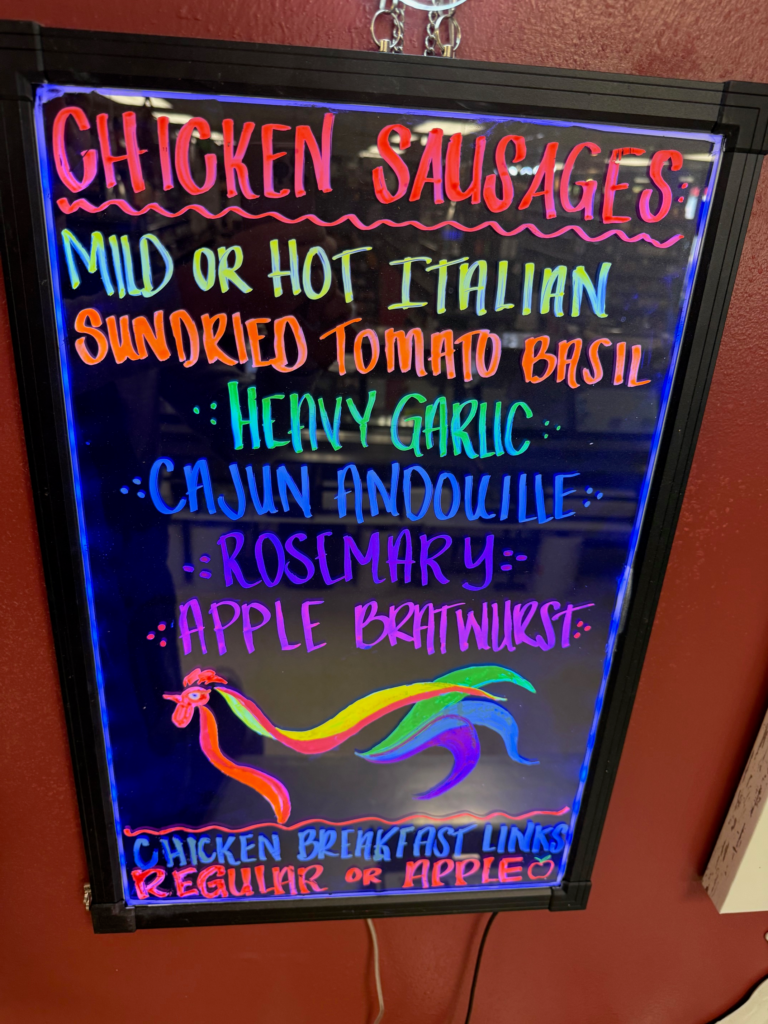 Chicken Sausage sign containing the flavors, mild italian, hot italian, sundried tomato basil, heavy garlic, cajun andouille, rosemary, apple breakfast links, regular links, or chicken apple links.