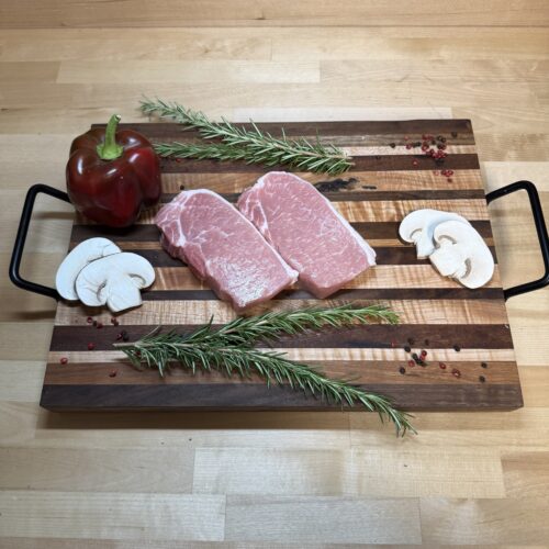 Two boneless pork chops on a board of garnishments