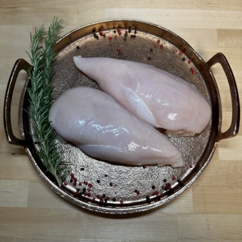 Two boneless chicken breasts on a tray of garnishments