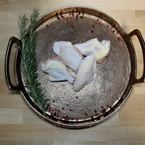 Four pieces of party wings which consist of wingettes and drummettes on a platter of garnishments