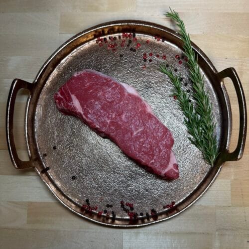 A new york steak on a tray of garnishments