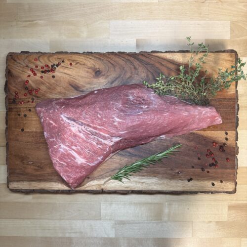 A tri tip roast on a board of garnishments