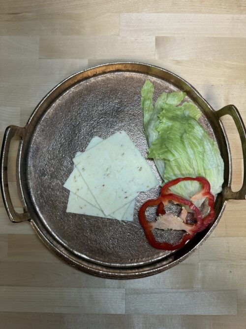 Sliced pepperjack cheese on a platter with bell pepper and lettuce as garnishment