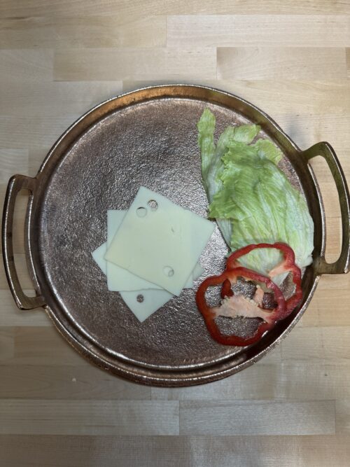 Sliced Swiss cheese on a platter with bell pepper and lettuce as a garnishment