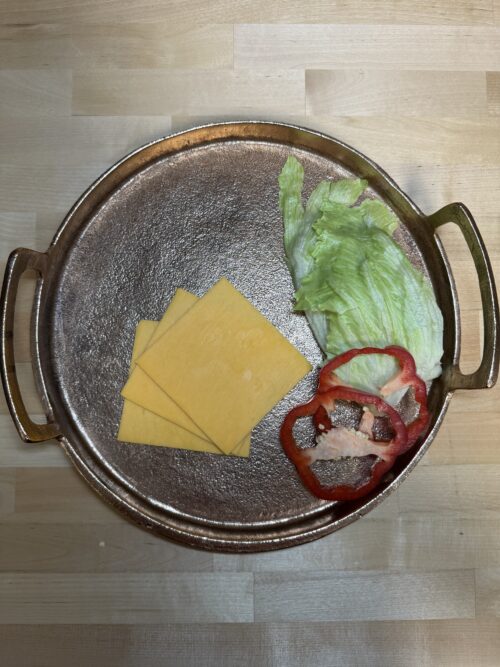 Cheddar Cheese on a platter next to bell pepper and lettuce slices used as garnishment